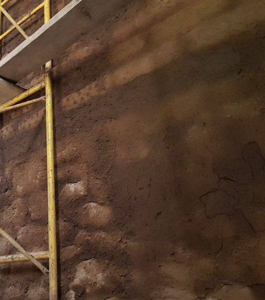 Muro de piedra de un templo antiguo con andamio durante su restauración
