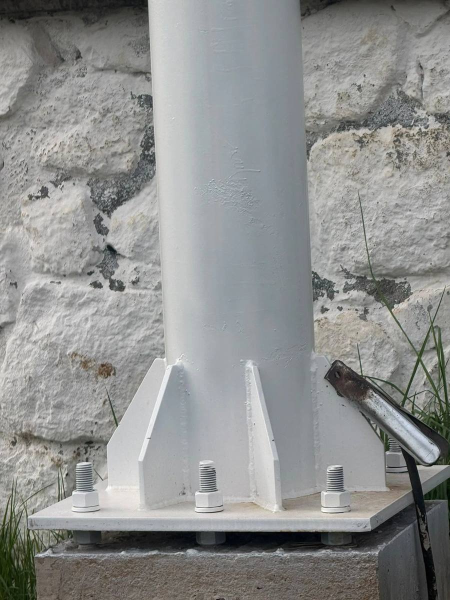 Base de columna metálica junto a un muro de piedra