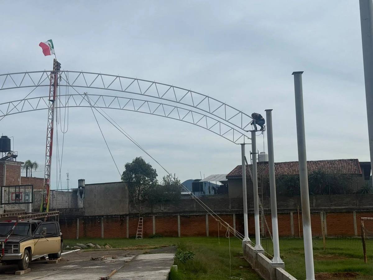 Arcos de techumbre terminados junto al asta bandera de una escuela